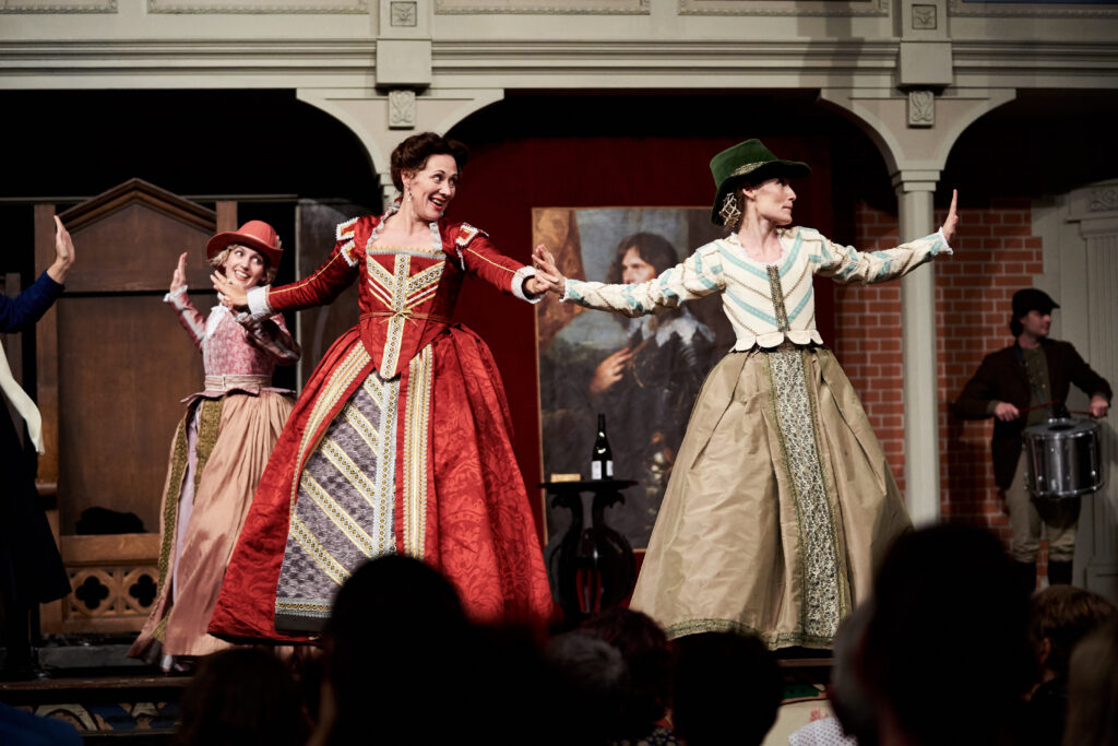 Actors in elizabethan dress on an Elizabethan stage dancing a jig 