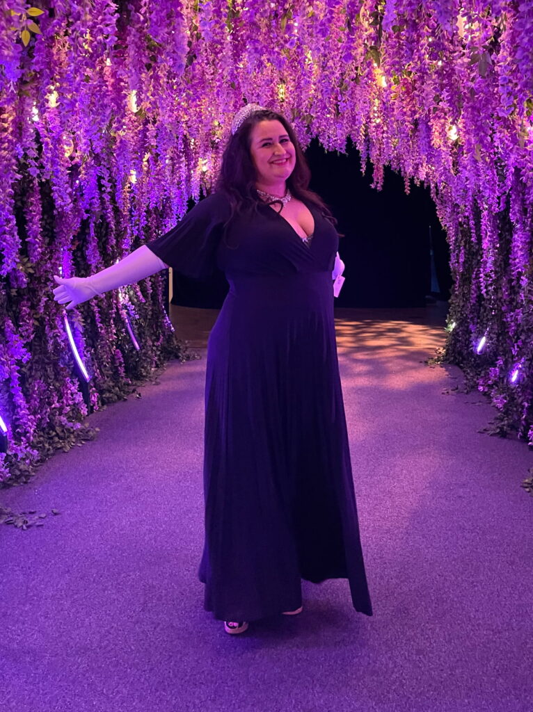 full length photo of Kathy smiling in a fuschia lit room